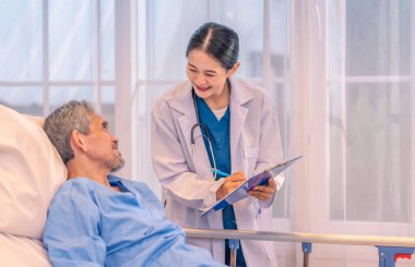 Önlüklü profesyonel kadın doktor hasta semptomlarını gözlemlemek için hasta raporunu bir panoya tutarak son sınıfları ziyaret ediyor.