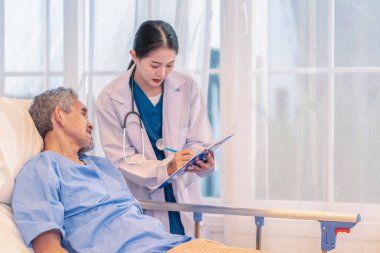 Önlüklü profesyonel kadın doktor hasta semptomlarını gözlemlemek için hasta raporunu bir panoya tutarak son sınıfları ziyaret ediyor.