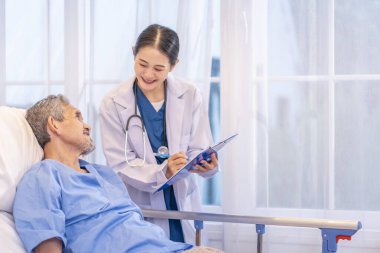 Önlüklü profesyonel kadın doktor hasta semptomlarını gözlemlemek için hasta raporunu bir panoya tutarak son sınıfları ziyaret ediyor.