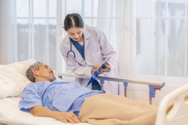 Önlüklü profesyonel kadın doktor hasta semptomlarını gözlemlemek için hasta raporunu bir panoya tutarak son sınıfları ziyaret ediyor.