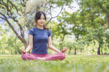 Parkta yoga yapan genç Asyalı kadın, insanların yaşam tarzı, egzersiz.
