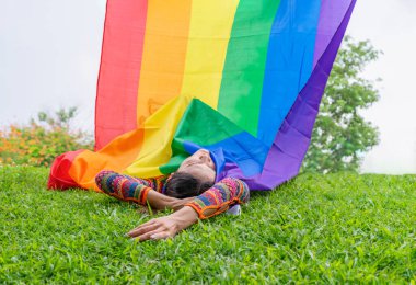 Igbtq gökkuşağı bayraklı yeşil çimlerin üzerinde uzanan transseksüel kadın vücudu, kavram lgbtq eşitlik hareketi, haklar, saygı