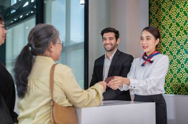 Havayolu görevlileri kuyrukta bekleyen yolculara pasaportlarını iade ediyorlar. Havaalanı kayıt bölümünde çalışan yer görevlileri, havayolu hizmetleri, hava taşımacılığı...