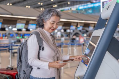 Sırt çantalı son sınıf bayan yolcu otomatta ya da havaalanı terminalindeki KIOSK kontrolünde kendini kontrol ederken, modern yaşam tarzı, teknoloji, ulaşım, seyahat gibi konularda emekli oldu.