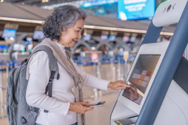 Sırt çantalı son sınıf bayan yolcu otomatta ya da havaalanı terminalindeki KIOSK kontrolünde kendini kontrol ederken, modern yaşam tarzı, teknoloji, ulaşım, seyahat gibi konularda emekli oldu.