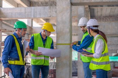 Binanın yapısını inceleyen mühendis ekibi yeni inşaat halinde. Tasarıya, inşaat mühendisliğine, iç teftişe, kalite kontrolüne göre şeritle beton kolonu ölçüyorlar. 