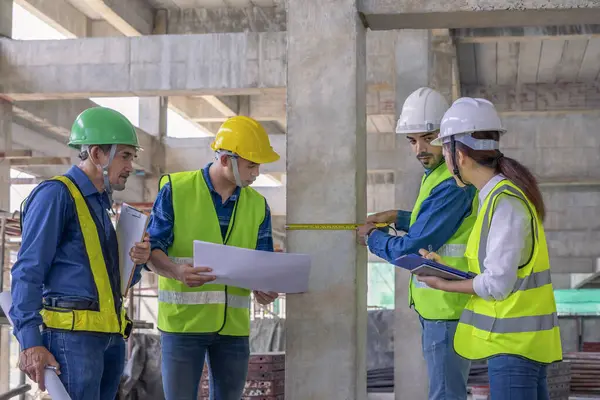Binanın yapısını inceleyen mühendis ekibi yeni inşaat halinde. Tasarıya, inşaat mühendisliğine, iç teftişe, kalite kontrolüne göre şeritle beton kolonu ölçüyorlar. 
