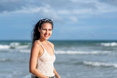 Tasasız genç bir kadın tasviri. Deniz kıyısında dikilmiş, yaz tatilinde deniz kenarında mutlu bir beyaz kadın turist.