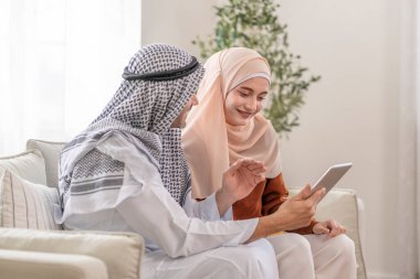 Genç Müslüman çift oturma odasında tablet kullanıyor.
