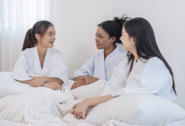 Bornozlu genç, çok ırklı arkadaşların portresi. Yatakta oturup, birlikte kutluyor, eğleniyor, gülüyor ve spa odasında dinleniyorlar.