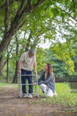 Doğa parkında dinlenen yaşlı bir adam otların üzerinde oturan ve babasının bacağına, kıdemli hastasına, iyileşme sürecine, rehabilitasyona, egzersiz yapmaya çalışan bir kızla konuşuyor.