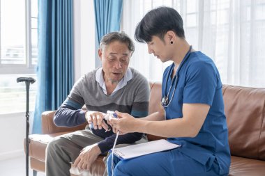 Erkek hemşire, ev ziyareti sırasında nabız oksimetrelerini ölçüyor.