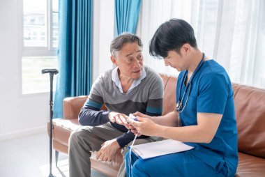 Erkek hemşire, ev ziyareti sırasında nabız oksimetrelerini ölçüyor.