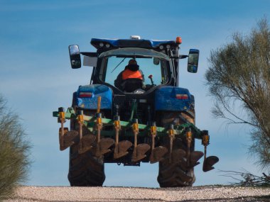 İspanya 'da hareket halindeki bir toprak yolda bir saban makinesiyle traktör.