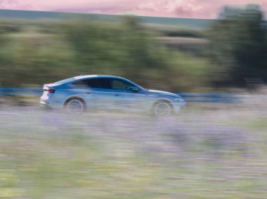 Otoyoldaki araba bitkilerin arka planına doğru hareket ediyor