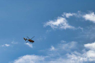 Helikopter beyaz bulutlu mavi gökyüzüne doğru uçuyor.