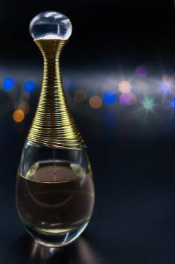 Siyah arka planda renkli ışıklarla aydınlatılmış bir şişe parfüm.