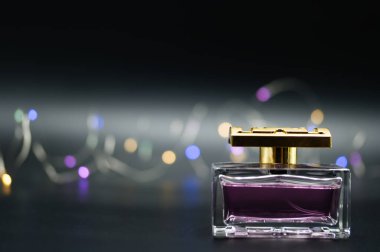 Siyah arka planda renkli ışıklarla aydınlatılmış bir şişe parfüm.