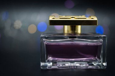 Siyah arka planda renkli ışıklarla aydınlatılmış bir şişe parfüm.