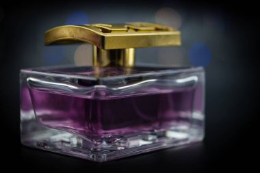 Siyah arka planda renkli ışıklarla aydınlatılmış bir şişe parfüm.