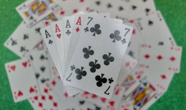 Parlak yeşil bir bezle oyun masasında kağıt oynarken.