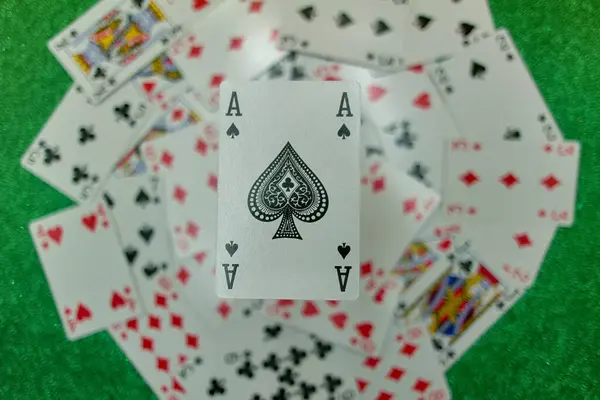 Parlak yeşil bir bezle oyun masasında kağıt oynarken.