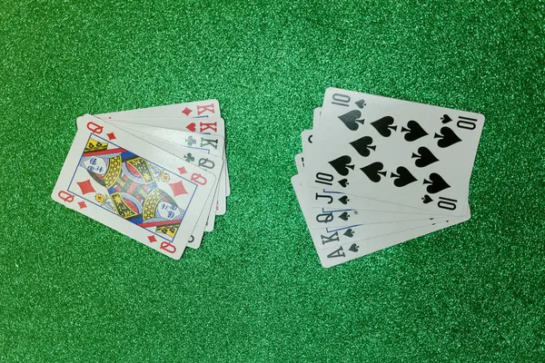 Parlak yeşil bir bezle oyun masasında kağıt oynarken.