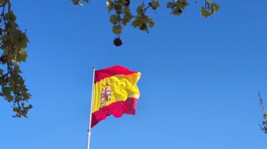 Sakin bir öğleden sonra açık mavi gökyüzünde dalgalanan İspanyol bayrağı