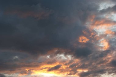 Güneş batarken gökyüzünü kaplayan bir dizi kara bulut sıcak turuncu tonlar ve gölgeler bırakıyor. Sahne, gece gündüz geçişi güzel bir renk gösterisiyle yakalar..