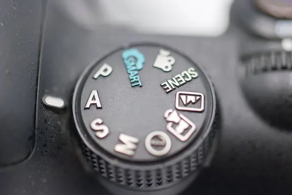 Kamera ayarlarının yakın görüntüsü, portre, manzara, gece ve otomatikman gibi farklı mod 'ları gösteriyor. Kadranda dijital bir kamera var. Detayları kaydediyor..