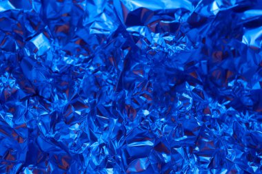 Buruşmuş mavi alüminyum folyo yüzeyi kaplayarak canlı ve parlak bir doku oluşturuyor. Işık metalik yüzeyden yansıyarak mavi tonunu ve karmaşık kıvrımlarını arttırır..