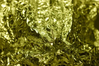 Pörsümüş altın folyo parlak bir şekilde aydınlatılır, parlak, yansıtıcı dokusu ve karmaşık kıvrımları sergilenir..