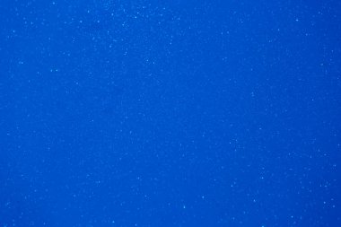 Derin mavi bir arkaplan, gün batımında huzurlu bir anı yakalıyormuş gibi titreyen parçacıkları etrafa saçıyor, sakinliği ve sakinliği çağrıştırıyor..