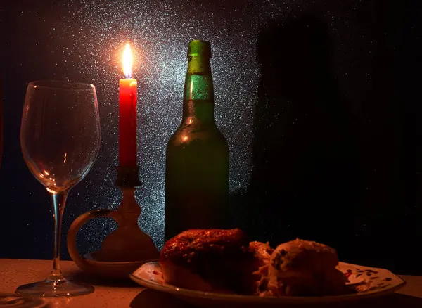 Sıcak bir akşam yemeği, bir mum, bir bardak şarap ve bir tabak yemeğin yanında bir şişe ile ayarlanır. Romantik bir akşam için mükemmel bir ortam yaratır..