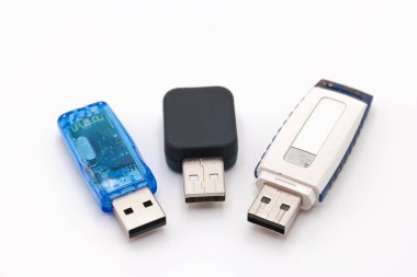Basit veri depolama çözümleri için farklı renk ve şekillere sahip düz beyaz arkaplan üzerinde düzenlenmiş üç farklı USB flaş bellek koleksiyonu.