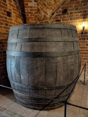 Geleneksel işçiliğin göstergesi olarak tuğla bir mahzende belirgin bir ahşap fıçı duruyor. Koyu renk ahşap, taş duvarlarla çelişiyor. Tarihi ve depolama tekniklerini koruyor..