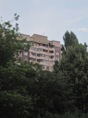 Yeşil ağaçlı pembe gökdelenli bina.