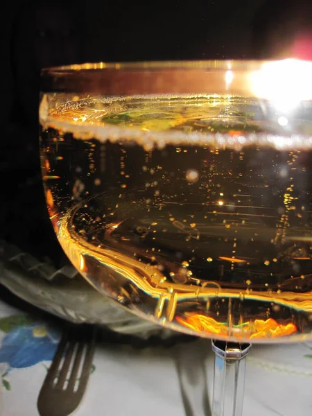 金色の縁を持つ広いガラスの中に泡と明るい輝く飲み物 — ストック写真
