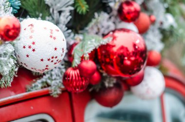 Karda Noel toplarıyla süslenmiş kırmızı bir klasik araba. Noel dekoru fotoğrafı.