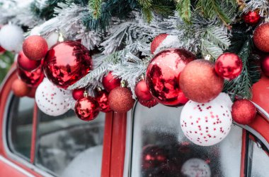 Karda Noel toplarıyla süslenmiş kırmızı bir klasik araba. Noel dekoru fotoğrafı.