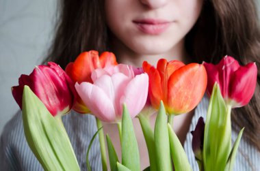 Bir buket kırmızı pembe laleli genç kız. Yumuşak bahar fotoğrafı.
