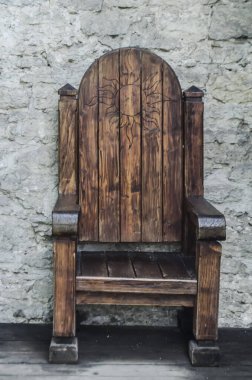 Antik oyulmuş tahta tahta ayaklıklar eski bir taş duvarın arka planında duruyor. Eski mobilya fotoğrafı..