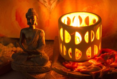 Seramik mum tutacağındaki bir mumun yanında bir Buda heykeli heykeli. Sunak fotoğrafı..