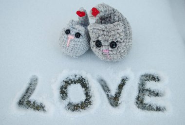 Kuyruğunda kırmızı kalp düğmeleri olan pelüş iplikten örülmüş gri kediler. Sevgililer Günü konsepti fotoğraf kış manzarası