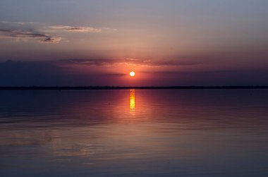 Deniz kıyısında günbatımı. Su elementinin fotoğraf uyumu.