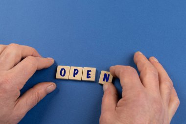 Açık kelimesi renkli bir yüzey üzerinde küçük ahşap tabletlerle oluşmuştur.