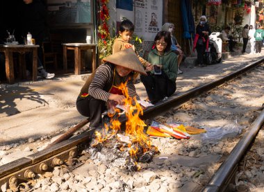  Hanoi, Vietnam. Ocak 2023. Tien am phu 'yu yakan bir kadın, şehrin eski çeyreğindeki evinin önündeki tren rayları boyunca atalarına adak adadı.