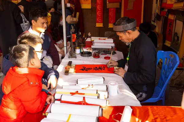 stock image Hanoi, Vietnam. Jnauary 2023. Man on the street writing auspicious words on red signs during Chinese New Year eve