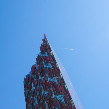 Modern binaların üstündeki mavi gökyüzünde bir uçağın geçişi.