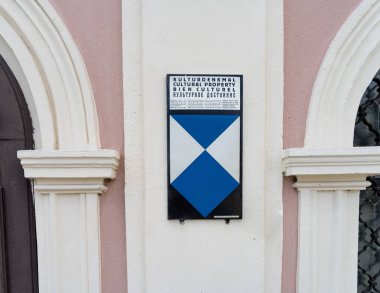 Villach, Avusturya. 18 Temmuz 2023 'te, silahlı çatışma durumunda kültürel malların korunması için Lahey tarafından korunan bir binadaki tabela.